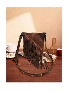 Close-up of deep brown suede tassel bucket bag with silver studs on a wooden table