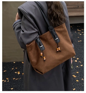 Dettaglio di borsa tote vintage in pelle scamosciata marrone con cinturini e nappe