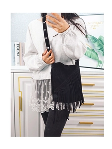 Detail of black suede fringe bucket bag with studded strap shown in mirror selfie