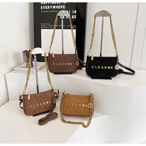 Detail view of frosted leather crossbody bags featuring gold chain handles and metal logos