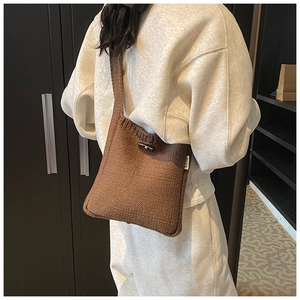 Détail d'un sac seau en tricot marron montrant la texture laine et le bouton cabillot