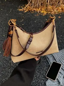 Minimalist beige suede hobo bag with dark brown leather trim and tassel on stone background