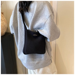 Détail d'un sac seau en tricot noir avec fermeture à bouton bascule en bois naturel