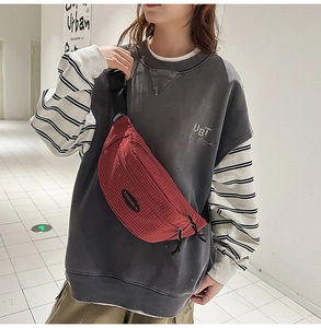 Crossbody view of a red checkered sports chest bag with adjustable black strap on a model
