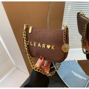 Detail of matte brown suede crossbody bag with gold metal chain and CLEAR logo