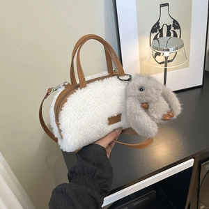 Close-up of white plush lamb wool handbag with brown leather strap and rabbit charm
