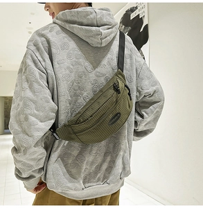 Detail of army green checkered nylon chest bag worn over a gray graphic sweatshirt