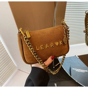 Close-up of brown suede shoulder bag with gold chain strap and metal logo hardware
