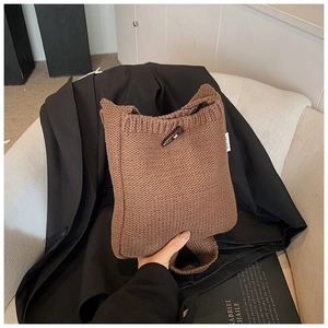 Détail d'un sac seau en tricot marron avec fermeture à bouton corne et texture tricotée