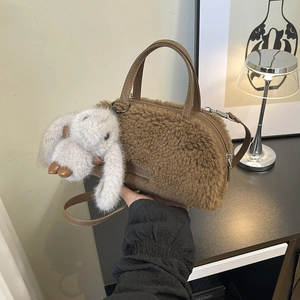Detailed close-up of brown faux shearling mini box bag with cute plush rabbit charm