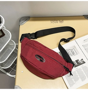 Detail of red checkered crossbody bag with adjustable nylon strap and safety buckle