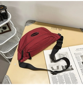 Detail of red checkered crossbody bag with adjustable nylon strap and plastic buckle