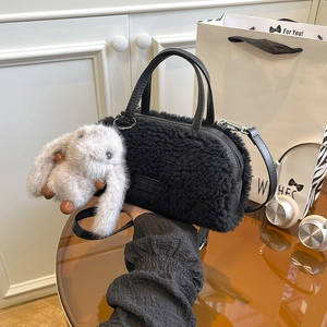 Detail of black lamb fleece bucket bag with leather brand tag and grey bunny charm accessory