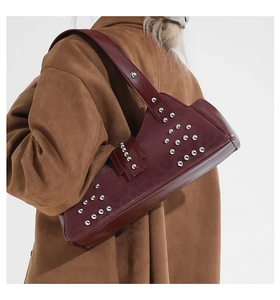 Détail du sac porté épaule bordeaux avec rivets vintage et bandoulière large