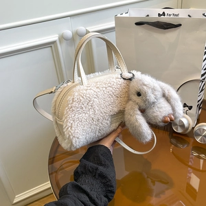 Detail of creamy plush cylinder bag with PU handle and cute long-eared rabbit charm
