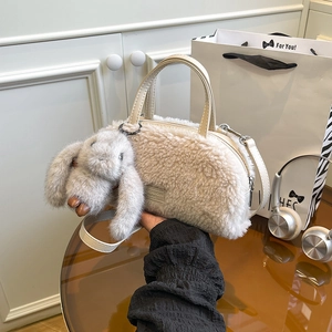 Detail of beige faux shearling mini box bag with plush bunny charm and shoulder strap