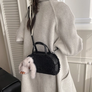 Detail of black faux fur box bag with leather handles and a plush rabbit charm