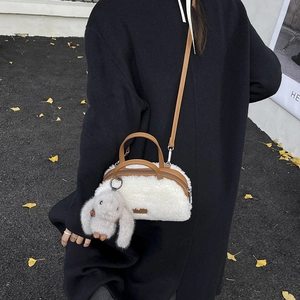Detail of white plush crossbody bag with brown leather straps and cute rabbit charm