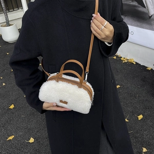Detail of white faux fur crossbody bag with brown leather handles and adjustable strap