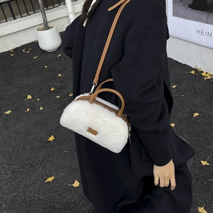 Detail view of the white plush crossbody bag with brown leather handles and strap