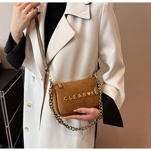 Detail view of brown suede crossbody bag with gold metal chain and CLEAR logo