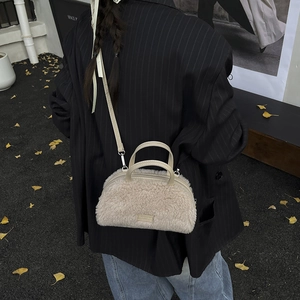 Detailed close-up of beige faux shearling mini crossbody bag with metal logo plate