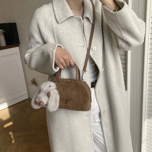 Detail of a brown faux fur mini bucket bag with leather strap and plush bunny charm