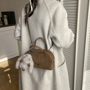Detail of brown plush cylinder bag with leather straps and a cute rabbit charm
