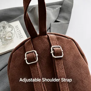 Detail of suede handbag showing adjustable shoulder straps with silver metal buckles