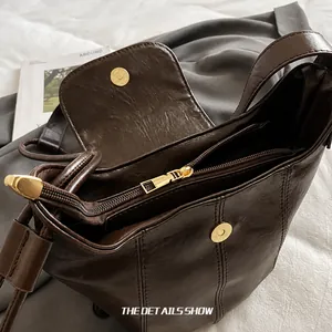 Detail der dunkelbraunen Lederbeuteltasche mit Goldmagnetverschluss und Innenreißverschluss