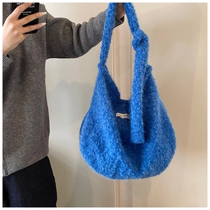 Detail of soft blue faux fur handbag featuring a plush texture and integrated handle