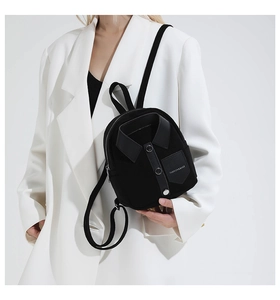 Close-up of black shirt-shaped mini backpack with collar and buttons on white blazer