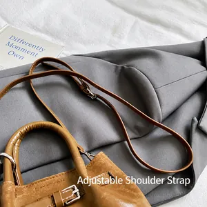 Detail view of the adjustable leather shoulder strap and metal buckle on brown bucket bag