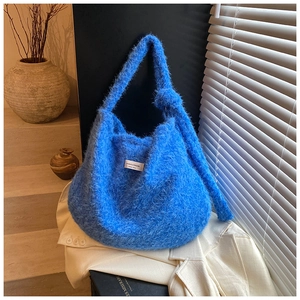 Détail du sac bandoulière en peluche bleue avec poignée nouée et étiquette tissée chic
