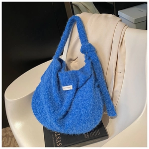 Blue fleece tote bag with brand label on a white chair over a black book