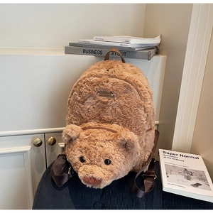 Close-up of brown plush teddy bear backpack with leather handle and metal brand plate