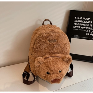 Close-up of caramel plush bear backpack featuring a metallic Lovely Bear logo plaque