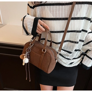 Borsa Boston scamosciata marrone con ciondolo da baseball indossata da una modella