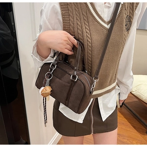 Dettaglio di una borsa Boston in pelle scamosciata testa di moro con ciondolo e tracolla