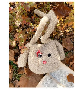 Dettaglio borsa shopper a forma di coniglio in peluche beige con fiocco rosso e foglie