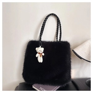 Detail einer schwarzen Kunstfell-Tasche mit geflochtenen Ledergriffen und Bärenanhänger