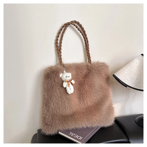 Detail einer flauschigen Plüsch-Tasche mit geflochtenen Griffen und Bären-Anhänger