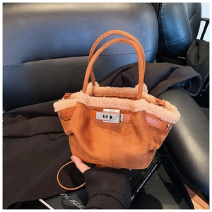 Close-up of brown suede handbag with plush fur trim and silver metallic twist lock closure