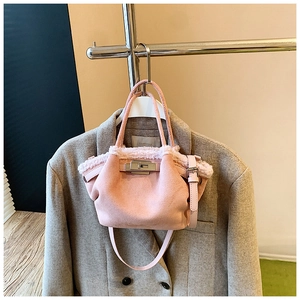 Close-up of pink crossbody bag with white plush trim and silver metallic twist lock