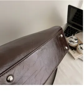Detailweergave van de donkerbruine vintage leren tasbodem met vier metalen beschermnopjes
