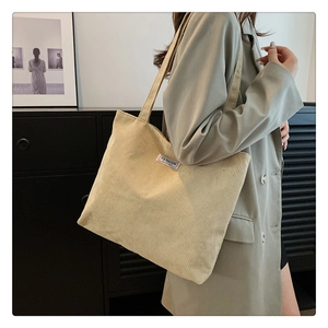 Detail of light beige corduroy tote bag showing the vertical texture and Fashion label