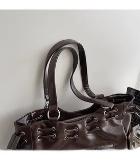 Detail van bruine draagtas met metalen oogjes en stevige handgrepen voor comfort