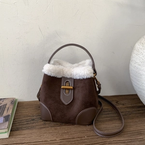 Détail du sac seau en daim d'hiver avec fourrure blanche et fermoir doré chic