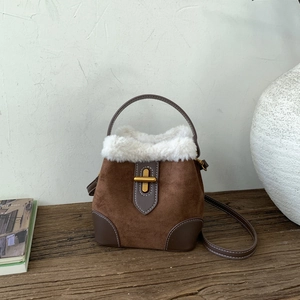 Détail d'un sac seau en daim marron avec bordure en fourrure blanche et fermoir doré