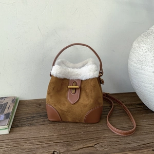 Détail du sac seau en daim marron avec bordure en peluche blanche et fermoir doré